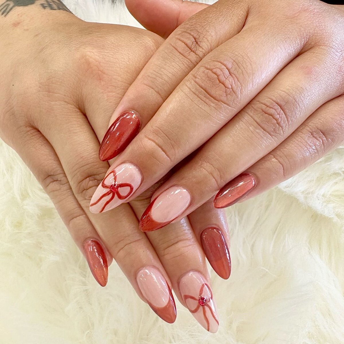 Cherry red almond nails with hand-painted bow accents